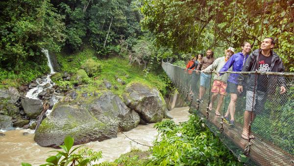 Travellers and CEO crossing a suspension bridge at Pacuare river, Costa Rica