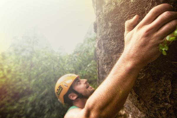 young man climbing a vertical rock wall