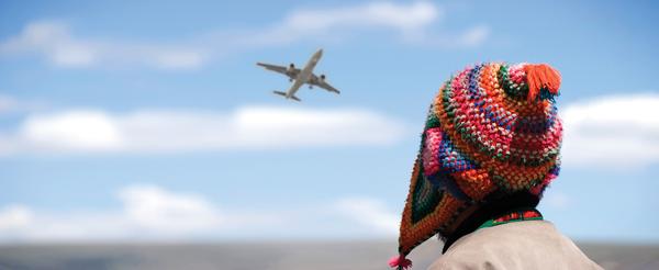 person wearing a knitted cap, watching an airplane take off
